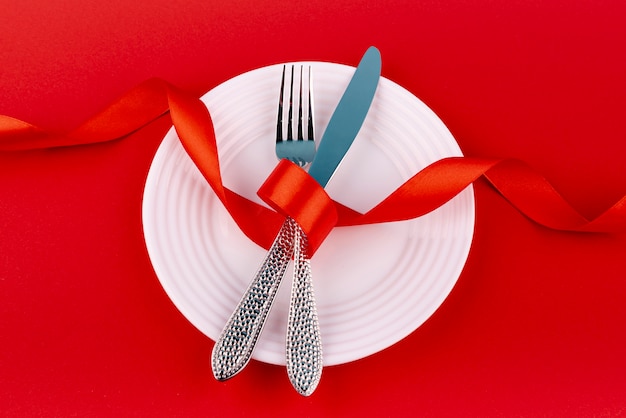 Free photo top view of cutlery on plate with ribbon