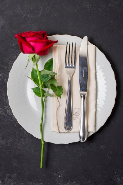 Top view cutlery with a rose on a plate