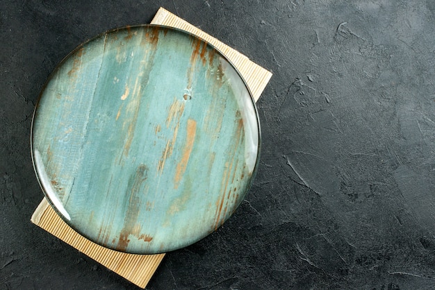 Top view cyan round platter beige board on black table with free space