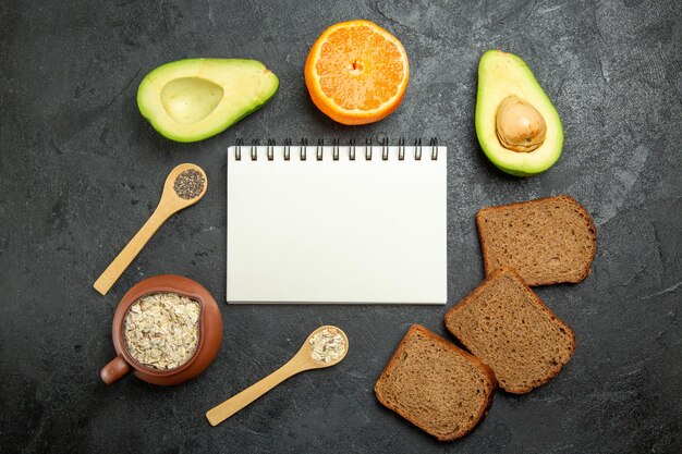 Top view of dark bread loafs with avocado on grey surface