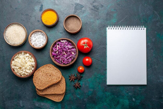 Top view dark bread loafs with seasonings and sliced cabbage on dark blue desk vegetable food meal dish bread color