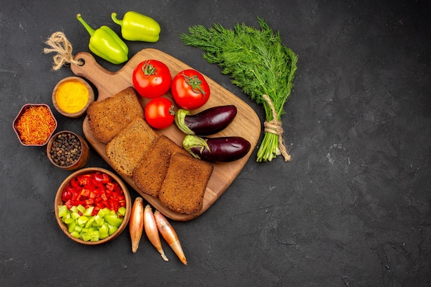 Free photo top view dark bread loafs with seasonings tomatoes and eggplants on dark background salad health ripe meal