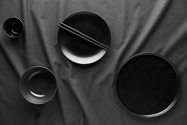 Вид сверху темных тарелок и палочек для еды