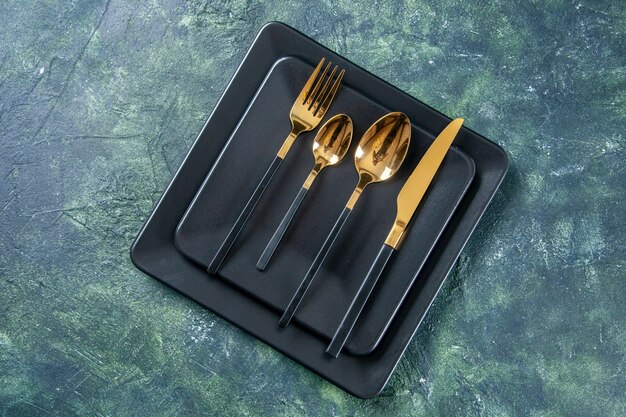 top view dark plates with golden spoons fork and knife on dark blue surface food cutlery color cafe kitchen restaurant darkness