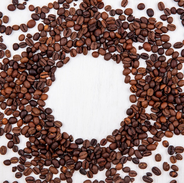 Top view of dark roasted coffee beans isolated on a circle shape on a white background with copy space