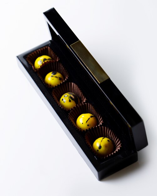 Top view decorated yellow speckled chocolate candy in a black gold box