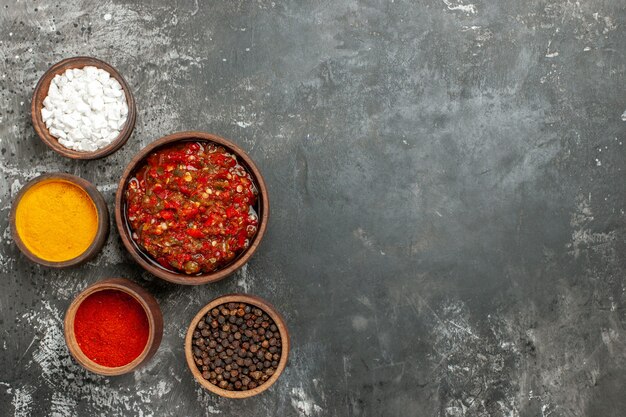 Top view delicious adjika different spices in small bawls on grey background
