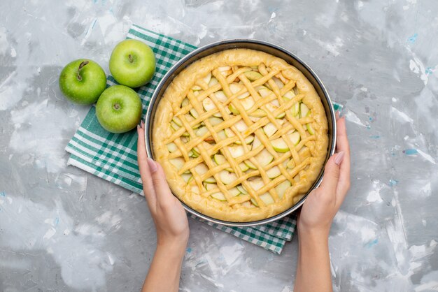 Вид сверху вкусный яблочный пирог круглый сформированный внутри сковороды со свежим зеленым яблоком, бисквитом