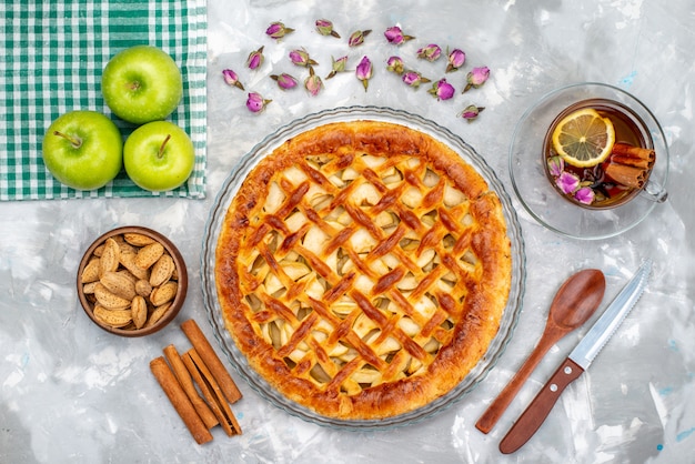 Foto gratuita una deliziosa torta di mele vista dall'alto con tè di mele verdi fresche e frutta zucchero biscotto torta alla cannella