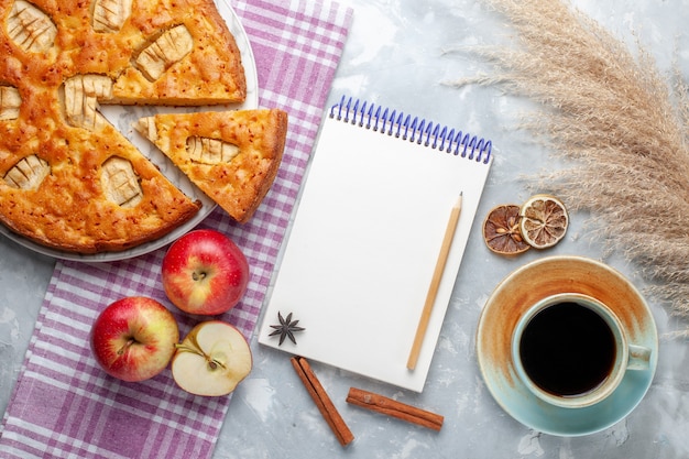 Free photo top view delicious apple pie inside plate with apples notepad and cup of tea on light background cake biscuit pie sweet