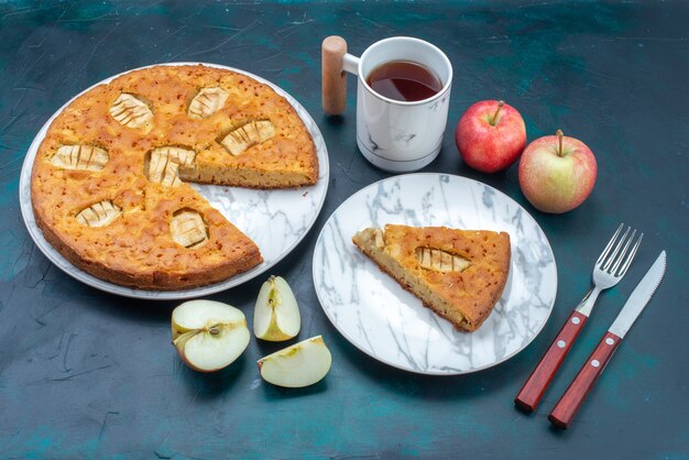 Вид сверху вкусный яблочный пирог нарезанный и целый с чаем яблоки на темном фоне фруктовый торт пирог сахар сладкий