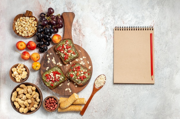 Free photo top view of delicious avocado sandwiches with grapes and nuts on a white surface