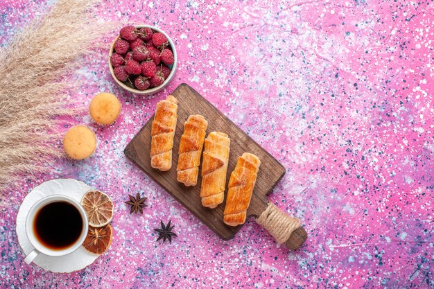 Vista dall'alto di deliziosi bagel con una tazza di tè sulla superficie rosa