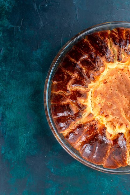 上面図水色の背景にガラス鍋の内側に甘い焼き菓子を丸く形成したおいしい焼き菓子。