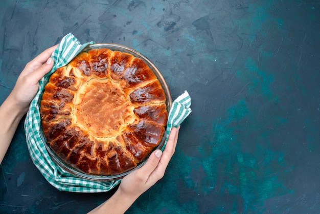 Top view delicious baked cake round formed sweet inside glass pan on the light blue background.