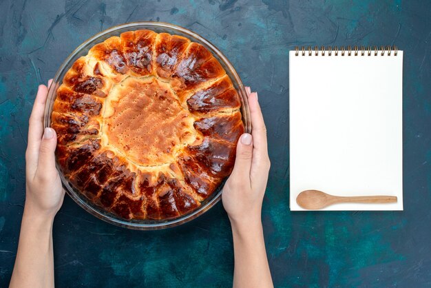 Вид сверху вкусный выпеченный торт круглой формы сладкий внутри стеклянной сковороды на голубом столе.