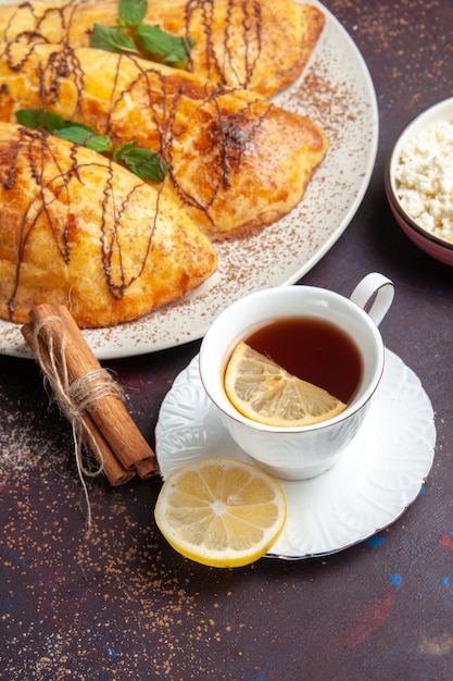 Foto gratuita vista dall'alto deliziosi dolci al forno con una tazza di tè sulla scrivania scura