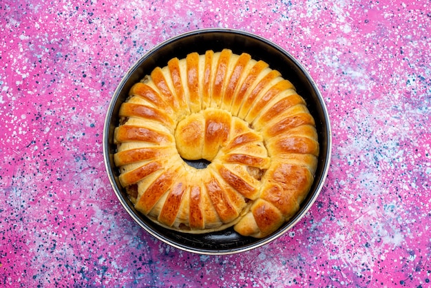 Top view of delicious baked pastry bangle formed inside pan on bright desk, pastry cookie biscuit sweet sugar