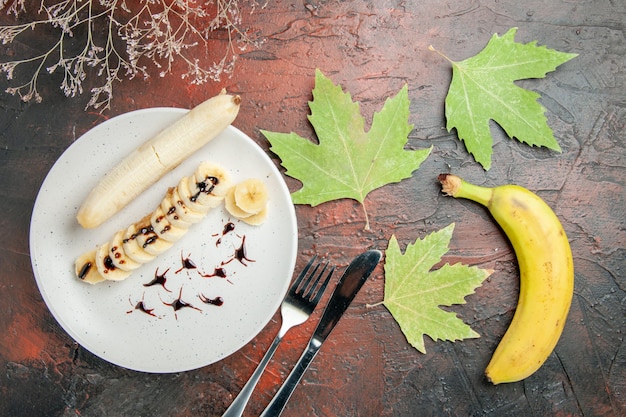 Вид сверху вкусный банан с нарезанными кусочками внутри тарелки на темном фоне