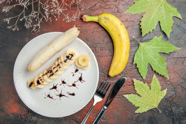 Vista dall'alto deliziosa banana con pezzi a fette all'interno del piatto sulla scrivania scura