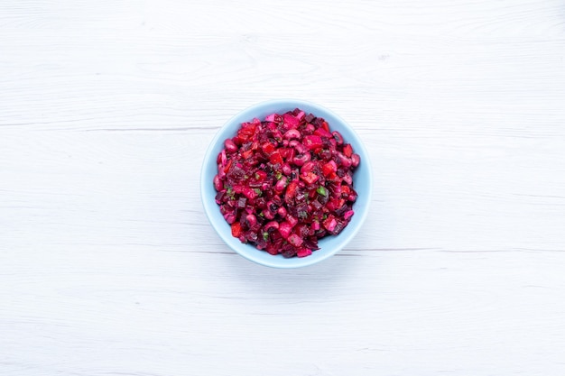 top view of delicious beet salad sliced with greens inside blue plate on light floor vegetable vitamine food meal health salad