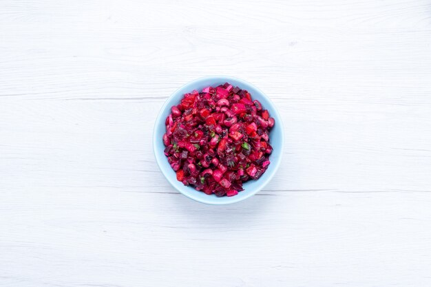 top view of delicious beet salad sliced with greens inside blue plate on light floor vegetable vitamine food meal health salad