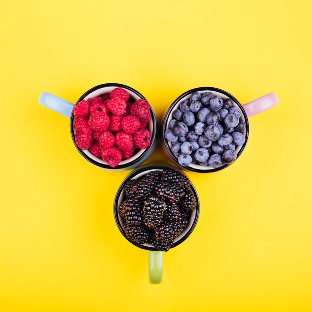 Top view of delicious berries in mugs