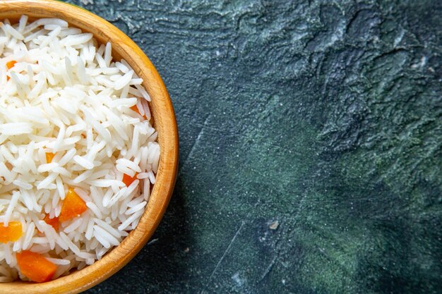 Вид сверху вкусный отварной рис внутри маленькой тарелки на темном столе