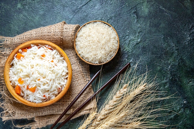 어두운 책상에 작은 접시 안에 원시 쌀과 상위 뷰 맛있는 삶은 쌀