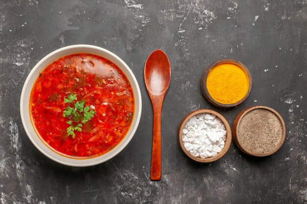 Top view of delicious borsch with seasonings on a dark surface