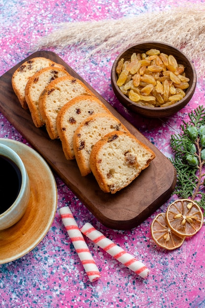 Vista dall'alto una deliziosa torta a fette di torta con uvetta e con la tazza di caffè sulla superficie rosa cuocere il biscotto dolce zucchero torta