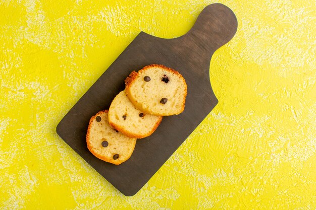 Top view of delicious cake slices on the brown wooden surface and yellow surface