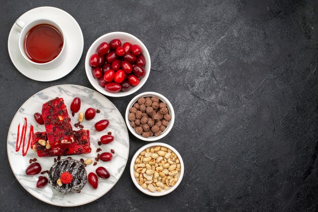 Top view delicious cake slices fruity cake with nuts and cup of tea on grey space