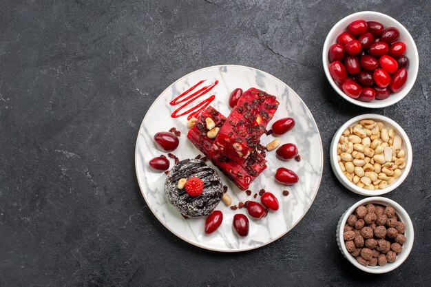 Top view delicious cake slices with nuts and dogwoods on a grey space