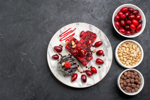 Top view delicious cake slices with nuts and dogwoods on a grey space