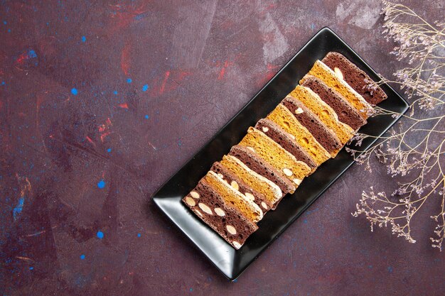 Вид сверху вкусные кусочки торта с орехами внутри формы для торта на темном фоне сладкий чайный торт сахарное печенье пирог бисквит