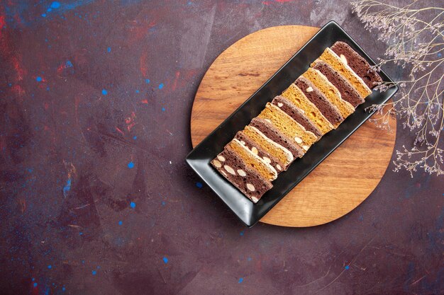 Вид сверху вкусные кусочки торта с орехами внутри формы для торта на темном фоне сладкий чайный торт сахарное печенье пирог бисквит