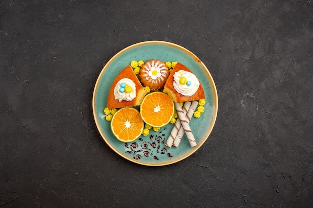 Top view delicious cake slices with pipe cookies and sliced tangerines on a dark background fruit citrus cake pie cookie sweet tea