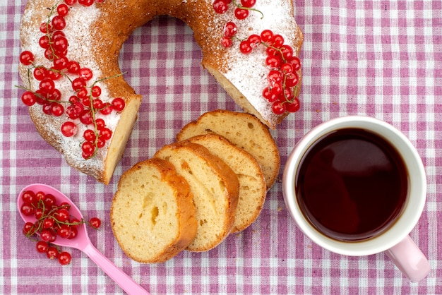 A top view delicious cake with fresh red cranberries cinnamon and tea on the purple tissue cake biscuit tea berry sugar