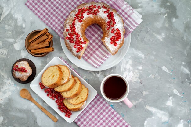 白いデスクケーキビスケットティーベリーシュガーの上の新鮮な赤いクランベリーシナモンとお茶の平面図おいしいケーキ