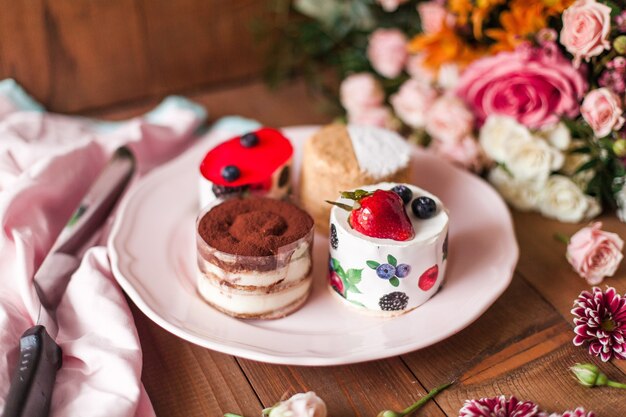 Top view of a delicious cake with icing on top near colorful flower decorations on a wooden table