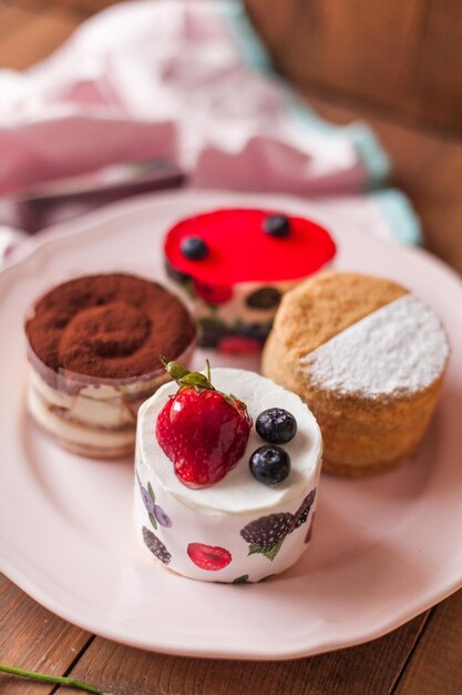 Top view of a delicious cake with icing on top near colorful flower decorations on a wooden table