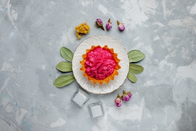 Top view of delicious cake with pink cream and chocolates on light desk, cake biscuit sweet bake cream