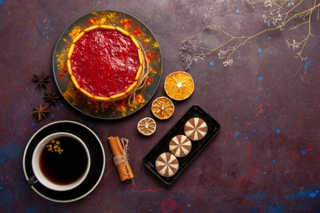 Top view delicious cake with red cream cookies and cup of coffee on dark background biscuit cake sugar dessert pie sweet cookies