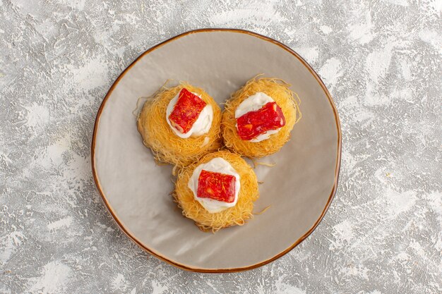 Top view of delicious cake with white cream and red marmalade inside plate