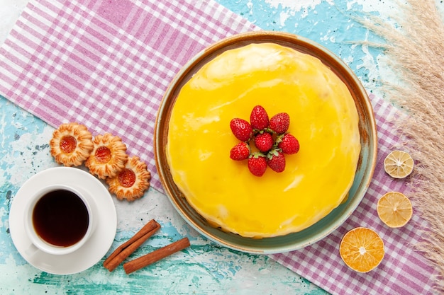 밝은 파란색 표면 비스킷 케이크에 노란색 시럽과 신선한 빨간 딸기가있는 상위 뷰 맛있는 케이크 달콤한 설탕 파이 차를 구워