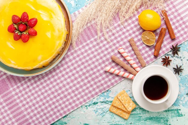 Top view delicious cake with yellow syrup and cup of tea on the light blue desk biscuit cake sweet pie cookies sugar tea