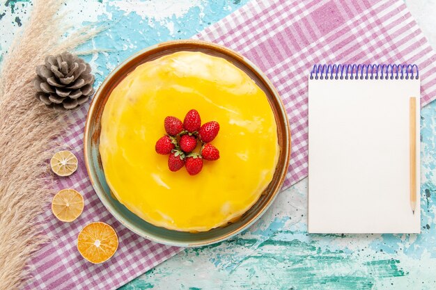 Вид сверху вкусный торт с желтым сиропом и свежей красной клубникой на голубой поверхности бисквитного торта испечь сладкий сахарный пирог чай