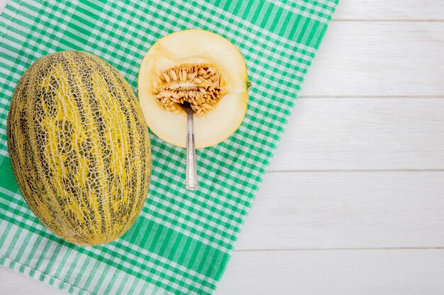 Top view of delicious cantaloupe melon on yellow checked tablecloth on white wood with copy space