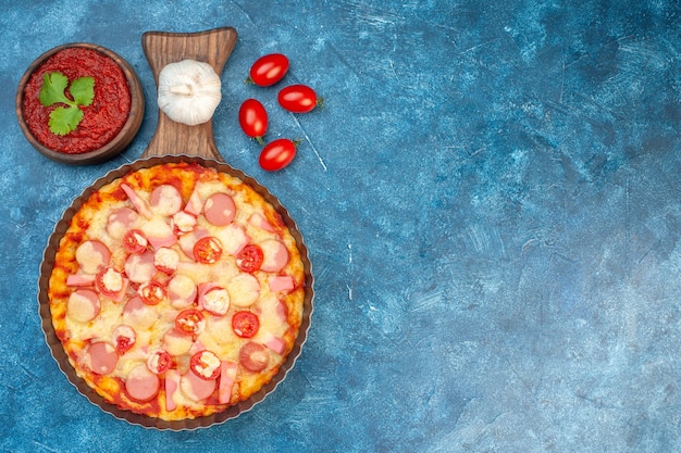 Vista dall'alto deliziosa pizza al formaggio con salsicce e pomodori su sfondo blu cibo italiano torta di pasta fast-food foto colore posto libero Foto Gratuite